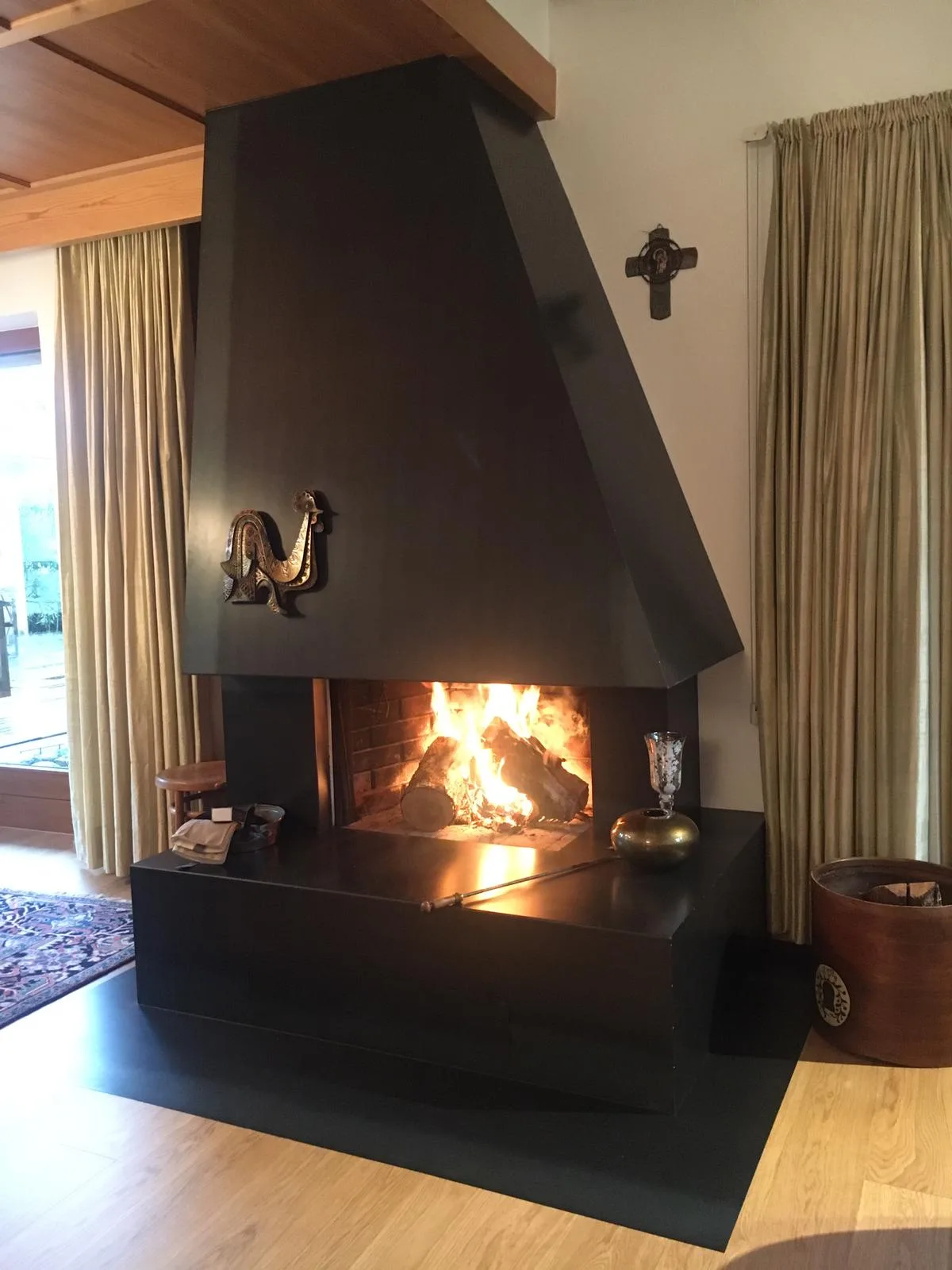 Offener Kamin mit großem schwarzem Stahlmantel in einem Wohnzimmer mit Holzdecke